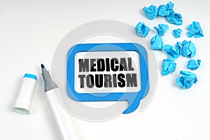On a white surface are crumpled blue paper, a marker and a sign inside which is written - MEDICAL TOURISM