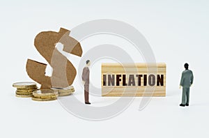 On a white surface, a dollar symbol, a figurine of businessmen and a wooden sign with the inscription - inflation