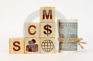 On a white surface, dollars and cubes with images and the inscription - SCM