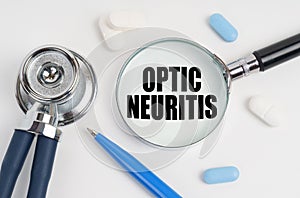 On a white surface lie pills, a pen, a stethoscope and a magnifying glass with the inscription - Optic neuritis