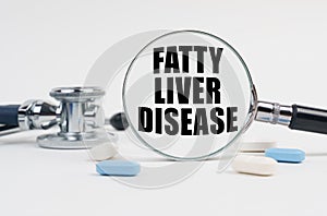 On a white surface lie pills, a stethoscope and a magnifying glass with the inscription - FATTY LIVER DISEASE