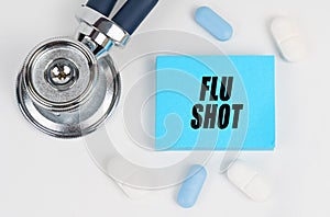 On a white surface lie pills, a stethoscope and stickers with the inscription - Flu Shot