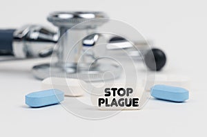 On a white surface lie pills, a stethoscope and a tablet with the inscription - STOP PLAGUE