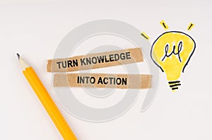 On a white surface, a luminous light bulb and pieces of paper with the inscription - turn knowledge into action