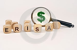 On a white surface, a magnifying glass with a dollar symbol and cubes with the inscription - ERISA