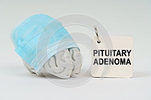 On a white surface next to the brain there is a notepad with the inscription - Pituitary adenoma