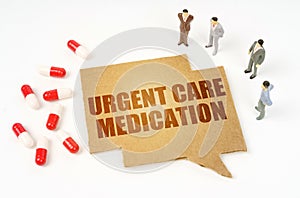 On a white surface are pills, a pen, figurines of people, a sign with the inscription - URGENT CARE MEDICATION