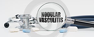 On a white surface are pills, a stethoscope and a magnifying glass inside which is written - Nodular vasculitis