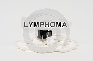 On a white surface are pills and torn paper with the inscription - LYMPHOMA