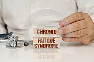 On a white surface, a stethoscope and wooden plates with the inscription - chronic fatigue syndrome