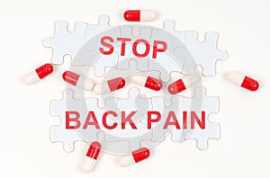 On a white surface, tablets and puzzles with the inscription - STOP BACK PAIN