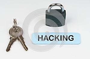 On a white surface there is a lock, keys and a blue sign with the inscription - Hacking