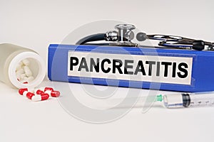 On a white surface there are pills, a syringe and a folder with the inscription - Pancreatitis