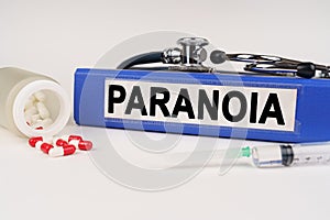 On a white surface there are pills, a syringe and a folder with the inscription - Paranoia
