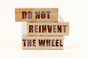On a white surface are wooden blocks with the inscription - Do Not Reinvent The Wheel