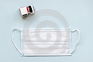 White surgical face mask and ambulance car on blue