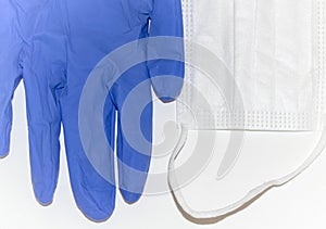 White surgical mask and blue latex gloves on a purple surface. Concept of Covid-19, coronavirus
