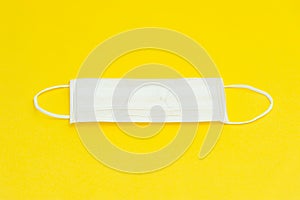 White surgical mask for protection against Coronavirus COVID-19 and other contagious diseases. Isolated on yellow background