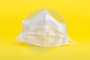 White surgical mask for protection against Coronavirus COVID-19 and other contagious diseases. Isolated on yellow background