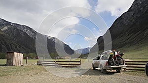 The white suv car with bicycles in pickup box arrives to the camping in the mountain valley.