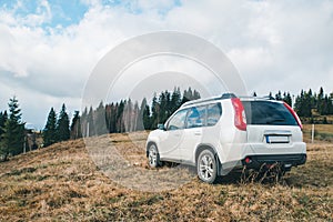 White suv car at top of the hill mountains on background