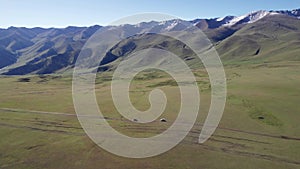 A white SUV drives through mountain green fields