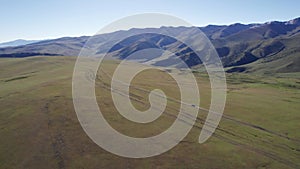 A white SUV drives through mountain green fields