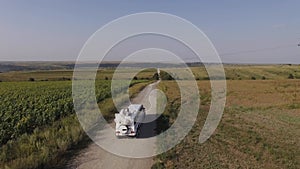 white suv limousine rides on the road in field. Aerial shot