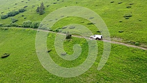 White SUV rides on a mountainous terrain on a dirt road.