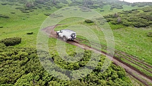 White SUV rides on a mountainous terrain on a dirt road.