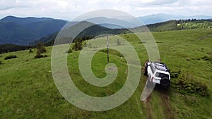 White SUV rides on a mountainous terrain on a dirt road.