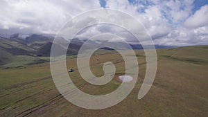 A white SUV rides in the mountains through fields