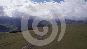 A white SUV rides in the mountains through fields