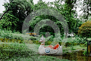 The white swan or duck pedal boat is moored in a lake in the park.