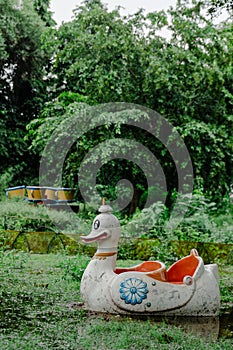 The white swan or duck pedal boat is moored in a lake in the park.