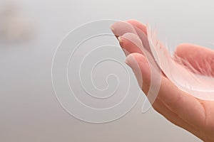 White swan feather on a hand of a white woman