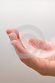 White swan feather on a hand of a white woman
