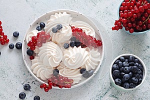 White sweet traditional merengues with berries on the plate