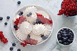 White sweet traditional merengues with berries on the plate