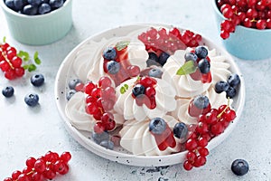 White sweet traditional merengues with berries on the plate