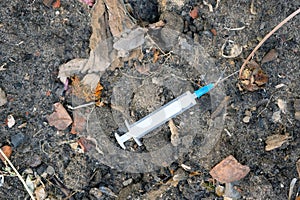 A white syringe lies on the ground top view.