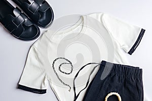 White T-shirt, black shorts or trousers, black slippers, necklace and bracelet. Overhead view of woman's casual day