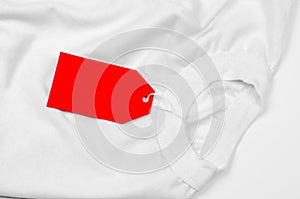 White t-shirt on a white background with a red blank label. Empty red price tag on a white t-shirt