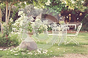 White table and chairs in beautiful garden. Vintage style pictures.