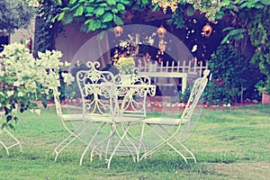 White table and chairs in beautiful garden. Vintage style pictures.