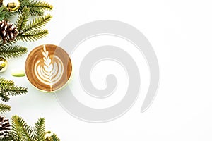 White table with cup of latte coffee and Christmas decoration with pine branches and pine cones. Christmas and new year