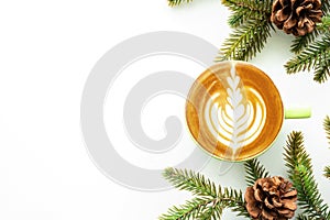 White table with cup of latte coffee and Christmas decoration with pine branches and pine cones. Christmas and new year