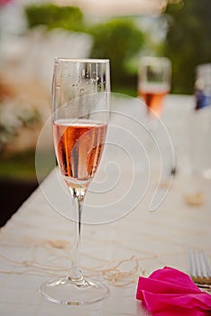White table decorated with pink napkin and a glass of sparkling wine.