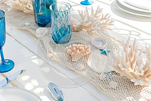 white table with fishnet runner, coral pieces, and blue glassware