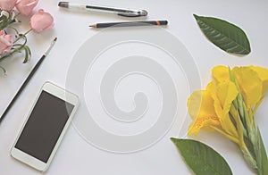 White table flat lay with flowers and leave blurred image.